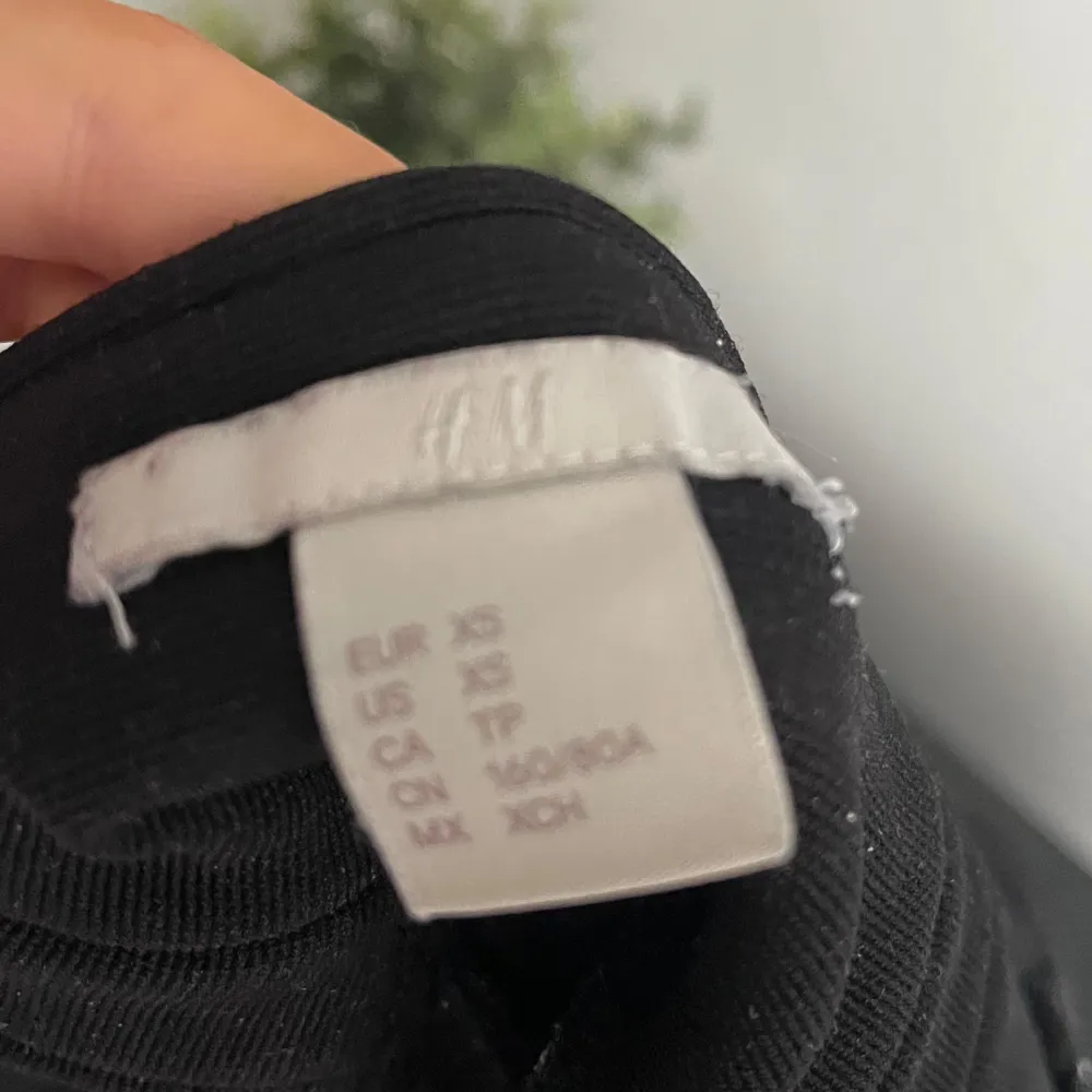 Säljer en svart croppad topp från H&M med breda axelband och omlott-design. Perfekt för en stilren look. Toppen är ärmlös och har en tight passform. Dragkedja på sidan. Yläosat.