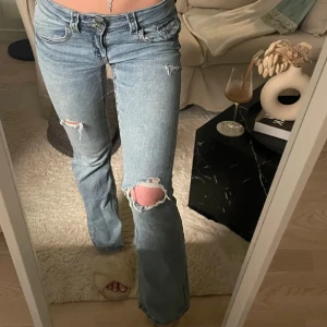 Blå bootcut jeans - Snygga blå bootcut jeans med slitningar på knäna. De har en låg midja och klassisk femficksdesign. 