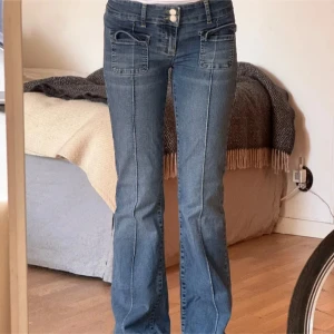 Blå bootcut jeans - Snygga blå bootcut jeans med låg midja och dubbla knappar fram. De har framträdande fickor och en klassisk jeanslook. Perfekta för en avslappnad stil.