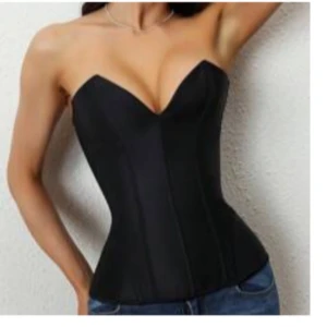 Svart axelbandslös korsett - Snygg svart korsett med en axelbandslös design som ger en elegant look. Perfekt för att skapa en smickrande siluett. Passar bra till både jeans och kjol. Har snören baktill som man kan spänna korsetten med. 