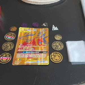 Pokémonkort Reshiram & Charizard GX - Säljer ett Pokémonkort med Reshiram & Charizard GX. Kortet har en färgglad design med guld och röd bakgrund. Det är en del av Tag Team-serien och har höga attackvärden. Perfekt för samlare eller spelare som vill stärka sin kortlek.