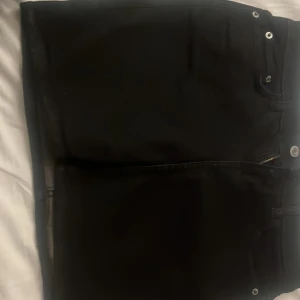 Svart jeans kjol från H&M - Snygga svarta byxor från H&M med klassisk design. Byxorna har en rak passform och är tillverkade i ett slitstarkt material. Perfekta för en stilren look.