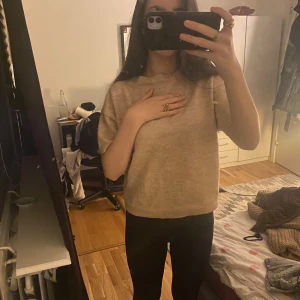 Beige stickad tröja - Säljer en mysig beige stickad tröja med korta ärmar. Perfekt för en avslappnad stil. Tröjan har en ribbad kant vid ärmslut och nederkant.