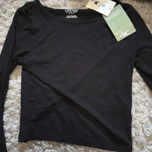 Svart långärmad topp från H&M - Säljer en stilren svart långärmad topp från H&M. Perfekt för en enkel och klassisk look. Tillverkad av återvunnen polyester, vilket gör den både snygg och hållbar. Passar ungdomar i åldern 13-14 år.