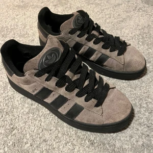 Charcoal/Svart Adidas Campus - Säljer nu dessa Adidas Campus i färgen Charcoal Black då de blivit för små. Jag har bevarat skorna så gott jag kan. På utsidan är de i väldigt bra skick med tanke på hur mycket jag använt de men på insidan har de båda två ett hål vid hälen (se bild 4 och 5).