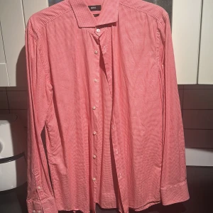Röd och vit rutig skjorta från Boss - Snygg röd och vit rutig skjorta från Boss i slim fit. Skjortan har långa ärmar och klassisk krage med knappar framtill. Perfekt för en stilren look.