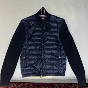 Moncler Cardigan  - Snygg marinblå Cardigan från Moncler med dragkedja och långärmade ärmar. Jackan är u ett väldigt bra skick, endast använd ett få tal gånger. Perfekt för våren och sommarkvällar!