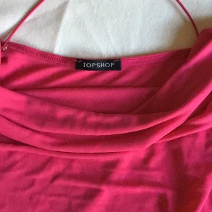 Rosa linnetopp från Topshop - Säljer en snygg rosa linnetopp från Topshop med tunna axelband och en draperad framsida. Toppen har en öppen rygg med korsade band för en stilren look. Perfekt för varma dagar eller en utekväll. Passar bra till både jeans och kjol!
