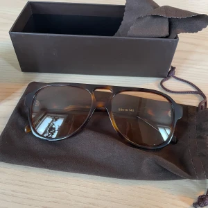 Gelo Tortoise Cinnamon Solglasögon från Corlin - Snygga solglasögon från Corlin i modellen Gelo Tortoise Cinnamon. De har en klassisk brun sköldpaddsmönstrad båge och bruna linser. Perfekta för en stilren look.