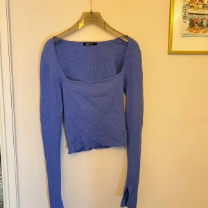 Blå ribbad topp från Gina Tricot - Säljer en snygg blå ribbad topp från Gina Tricot. Toppen har en fyrkantig urringning och långa ärmar, perfekt för en stilren look. Den är croppad och passar bra till både jeans och kjol. Perfekt för vårens garderob!