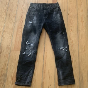 Svarta jeans från Supply & Demand - Snygga svarta jeans från Supply & Demand med slitna detaljer och en cool, tvättad look. Byxorna har en normal passform och är perfekta för en avslappnad stil. Märket är baserat i New York City och byxorna är i storlek XL för åldrarna 13-15.