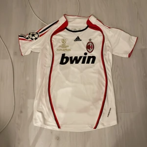 AC Milan Maldini Champions League tröja - Säljer denna AC Milan fotbollströja med Maldini 3 på ryggen, Champions League-märke på ärmen och Bwin som sponsor. Tröjan är vit med röda och svarta detaljer, klassisk Adidas-design och klubbmärke på bröstet. Skulle säga att den är medium