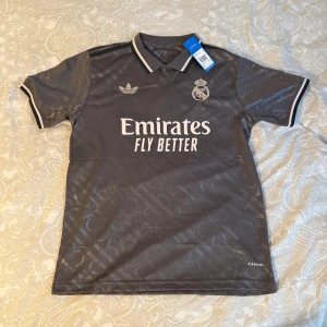 Real Madrid grå fotbollströja - Säljer en grå Real Madrid-tröja i storlek M. Tröjan är i helt nytt skick! Perfekt för alla fans! 
