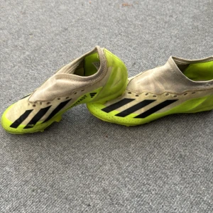 Adidas Crazyfast gula fotbollsskor - Säljer ett par Adidas Crazyfast fotbollsskor i en riktigt fet gul färg med svarta ränder. Skorna har låg profil, plös utan snörning och mönstrad sula med dobbar för gräsplan. Ovandelen är i syntetmaterial och insidan är fodrad i gult.