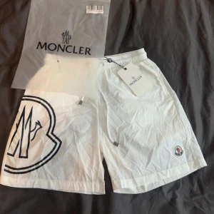 Moncler Badshorts Storlek M (OBS! SITTER SOM S ELLER XS)  - !!OBS SHORTSEN ÄR VÄLDIGT SMÅ I STORLEKEN!! Moncler vita badbyxor , skönt material elastisk midja.  Shortsen är aldrig använda och är helt sprillans nya.