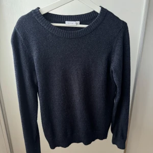 Mörkgrå stickad tröja från Vila - En enkel och stilren mörkgrå stickad tröja från Vila. Tröjan har rund halsringning, ribbade muddar och lång ärm. Perfekt för lager-på-lager och passar till både jeans och kjol. Klassisk modell som funkar året om. 