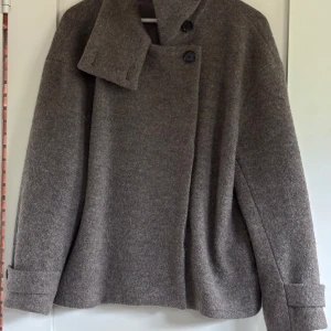 Brun ullkappa med stora slag - Snygg brun kappa i ull med oversized passform och stora slag. Kappan har dubbelknäppning med svarta knappar och bred krage som ger en cool look. Perfekt för höst och vinter när du vill vara både varm super snygg! 🤩 