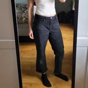 Svarta croppade jeans från Weekday - Säljer ett par tvättade svarta jeans från Weekday i modellen Voyage, strlk W30. De är högmidjade med croppad längd och råa, fransiga benslut. Jeansen har en rak och lite loose passform, klassiska femficksdetaljer och är tillverkade i bomull. Säljer pga att de är för stora, som referens är jag 178 cm och brukar bära W29. Mycket bra skick. Hör av dig med frågor, är öppen för prisförslag 🌸