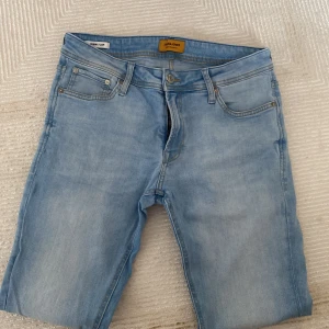 Ljusblå skinny jeans från Jack & Jones - Snygga ljusblå skinny jeans från Jack & Jones med klassisk femficksdesign och dragkedjegylf. Jeansen har en smal passform och är tillverkade i stretchigt denim för extra komfort. Perfekta för en avslappnad och trendig look.