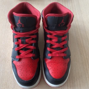 Nike Air Jordan 1 Mid Svart/Röd EUR 39 - Säljer ett par Nike Air Jordan 1 Mid i klassisk svart och röd färg. Skorna har röd swoosh, röda snören och detaljer, samt svart läder på sidor och tå. Ikonisk Jumpman-logga på plösen och Air Jordan-märke på sidan. Passar både kvinnor och män. Ordinarie pris 1300 men säljer billigare eftersom de har använts fåtal gånger. Skorna skickas i deras orginall box. 