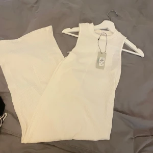 Vit ribbad ärmlös långklänning - Supersnygg vit långklänning från primark, i ribbat material. Klänningen är ärmlös med rund halsringning och har en stilren, enkel design som passar perfekt till sommaren. Skön och stretchig passform som känns både trendig och bekväm.