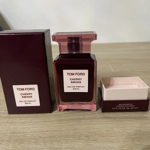 Tom Ford Cherry Smoke EdP 100ml - Tom Ford Cherry Smoke Eau de Parfum 100 ml. Flaskan är mörkröd med en stilren, fyrkantig design och matchande lock. Kommer i elegant vinröd kartong. Doften är känd för sina körsbärs- och rökiga toner, perfekt för dig som gillar unika och lyxiga parfymer.