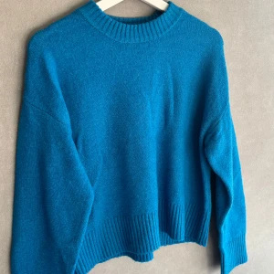 Blå stickad tröja med ribbade detaljer från Zara - En blå stickad tröja med ribbade detaljer runt hals, ärmslut och nederkant. Den är i storlek 152 (11-12år)