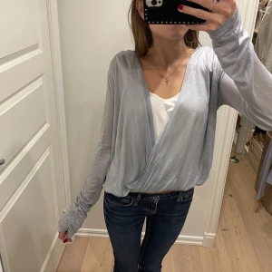 Omlottopp från Calvin Klein - Omlottopp från Calvin Klein i en ljusblå glittrig färg🥰I mycket bra skick förutom några små hål vid ena ärmen efter tvätt🌸💕