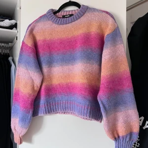 Färgglad stickad tröja från BikBok - Säljer en superfin stickad tröja från BikBok i storlek S. Tröjan har ett färgglatt randigt mönster i rosa, lila och orange toner. Den är croppad med långa ärmar och ribbade kanter. Perfekt för att liva upp garderoben! 🌈 Önskar du veta exakta mått? Tveka inte att höra av dig!