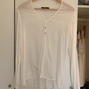 En vit blus  - En tunn och skön blus med knappar i ärm och fram. Fina detaljer i tyget. Det är ett tunt material så perfekt för sommaren!