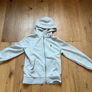 Grå polo ralph Lauren huvtröja  - En snygg polo ralph Lauren hoodie. De förliker tyvärr inte med org snören men kan föröka med andra snören. Hör av er om ni har några frågor.
