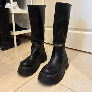 Svarta höga boots - Snygga svarta boots med en rejäl platåsula. De är knähöga. Perfekta för att ge lite edge till din outfit.