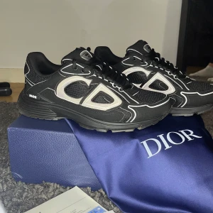 Dior b30 - Snygga svarta sneakers från Dior med vita detaljer och snörning. Skorna har en robust sula och en modern design som passar perfekt för en trendig look. Levereras med originalförpackning och tillbehör. Använd skorna en gång går att Sicka mer bilder om det behövs. Går ner i pris vid snabb affär 