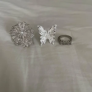 Tre silverfärgade ringar med olika designer - Säljer tre ringar då fjärilen och blomman är från lyxa och mom är från shein. Alla är bra skick då ingen är rostad eller har tappat färg💕