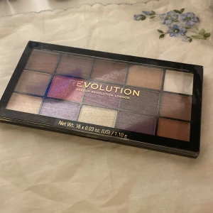 Ögonskuggspalett från Makeup Revolution - Säljer en ögonskuggspalett från Makeup Revolution, modell Reloaded Visionary. Paletten innehåller 15 olika nyanser i både matta och skimrande toner, perfekt för att skapa varierade looks. Färgerna sträcker sig från neutrala bruna och beige till djärva lila och guld. Endast använd 1-2 gånger