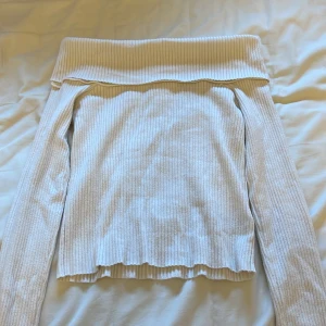 Vit ribbad offshoulder tröja från H&M - Säljer en stilren vit ribbad offshoulder tröja från H&M. Perfekt för en trendig look med långa ärmar och en bekväm passform. Passar utmärkt till både jeans och kjol. Hör av dig vid intresse! 🤍
