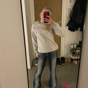 Grå hoodie från Gina Tricot - Säljer en grå hoodie från Gina Tricot med texten 'MA CHÉRIE' och en stjärna tryckt på både fram- och baksidan. Perfekt för en avslappnad stil. Hoodien har långa ärmar och en klassisk huva. Skön och enkel att matcha med jeans eller leggings.