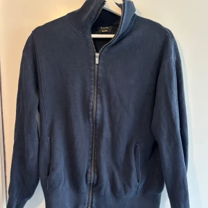  Massimo Dutti tröja - Säljer en stilren mörkblå tröja från Massimo Dutti i bomull. Tröjan har en dragkedja framtill och långa ärmar. Perfekt för en avslappnad och snygg look.