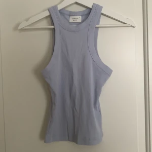 Ljusblå ribbad linnetopp - Säljer en ljusblå ribbad linnetopp från gina tricot. Toppen är ärmlös och har en tight passform, perfekt för sommardagar. Den är gjord i ett mjukt och stretchigt material. Använd 1 gång. 