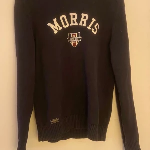 Mörkblå tröja från Morris - Säljer en snygg mörkblå tröja från Morris med vit text på bröstet. Tröjan har långa ärmar och en klassisk passform. Perfekt för en stilren look. Inga defekter alls!