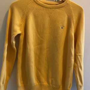 Gul tröja från GANT - Säljer en snygg gul tröja från GANT i storlek 146/152 cm. Tröjan har långa ärmar och ett diskret GANT-märke på bröstet. Perfekt för en stilren och bekväm look. Passar bra till både jeans och chinos.