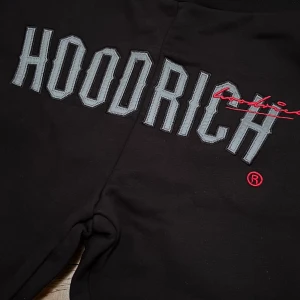 Svarta mjukisbyxor från Hoodrich - Snygga svarta mjukisbyxor från Hoodrich med reflekterande tryck. Byxorna har en elastisk midja med snörning för bästa passform. Perfekta för en avslappnad stil.