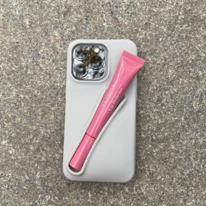 Mobilskal från Amore UF - Mobilskal med en inbyggd hållare för olika läppglans i färgen grå för IPhone 13/14/15 PLUS. Den rymmer flera olika läpprodukter och ger bra skydd för mobilen🥰🥰perfekt för tillfällen där du inte vill ha en väska med dig!