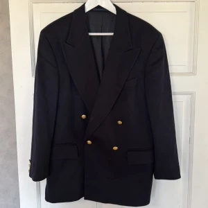 Hugo Boss klubb blazer (Loro Piana material) - En klassisk dubbelknäppt blazer med fina guldfärgade knappar. 75% virgin wool och 25% cashmere blend från Loro Piana. Fickor framtill och innanför. Kavajen utstrålar massvis med elegans.