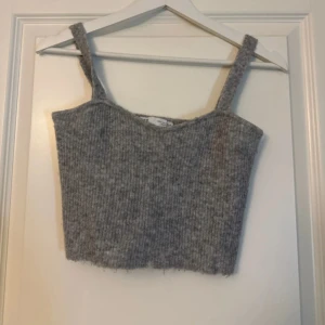 Grå ribbad linnetopp från Zara - Säljer en stilren grå ribbad linnetopp från Zara. Toppen har breda axelband och en croppad passform, perfekt för lager på lager eller som den är. Ett mångsidigt plagg för garderoben!