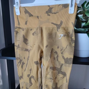 Kamouflage leggings från Gymshark i storlek XS - Gula camo leggings från märket Gymshark. Storlek XS. Helt nya utan lapp. Loggor intakta. Snygg scrunch-detalj bak på rumpan.