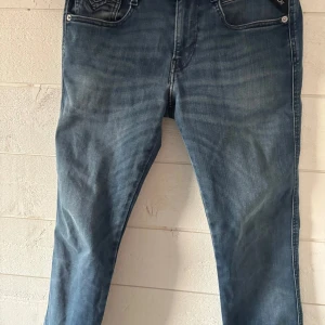 Blå jeans från Replay - Snygga blå jeans från Replay i modellen Anbass, en smalare modell. Byxorna är i storleken 29/32 och är använda ett fåtal gånger. De har en klassisk femficksdesign och en bekväm passform i stretch. Perfekta för en avslappnad stil. Dom finns endast ute för 300kr.