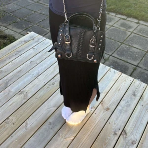 Svart axelväska från zara - Snygg svart axelväska i skinn med kedjedetaljer och dekorativa spännen. Väskan har en dragkedja upptill och är perfekt för att ge en edgy touch till din outfit. Den har också en justerbar axelrem för bekväm användning. Aldrig använd!