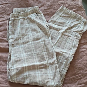 Beige randiga byxor från Lindex - Säljer ett par bekväma beige byxor från Lindex med randigt mönster. Byxorna har en elastisk midja för extra komfort och är perfekta för en avslappnad stil.