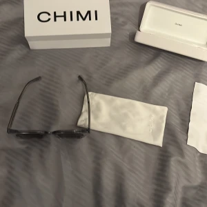 Grå solglasögon från CHIMI 04 Gray - Snygga grå solglasögon från CHIMI med en stilren och modern design. De har en fyrkantig form och kommer med ett matchande fodral. Perfekta för att ge din outfit en cool touch. Allt medföljer. Inte andvöbda särkilt mycket ungefär en halv sommar om ens det. Säljer på grund av att jag inte passar eller gillar dem. Vill gärna bli av med dem, inga defekter eller skador. Priset är inte hugget i sten. Tveka inte på att höra av er!